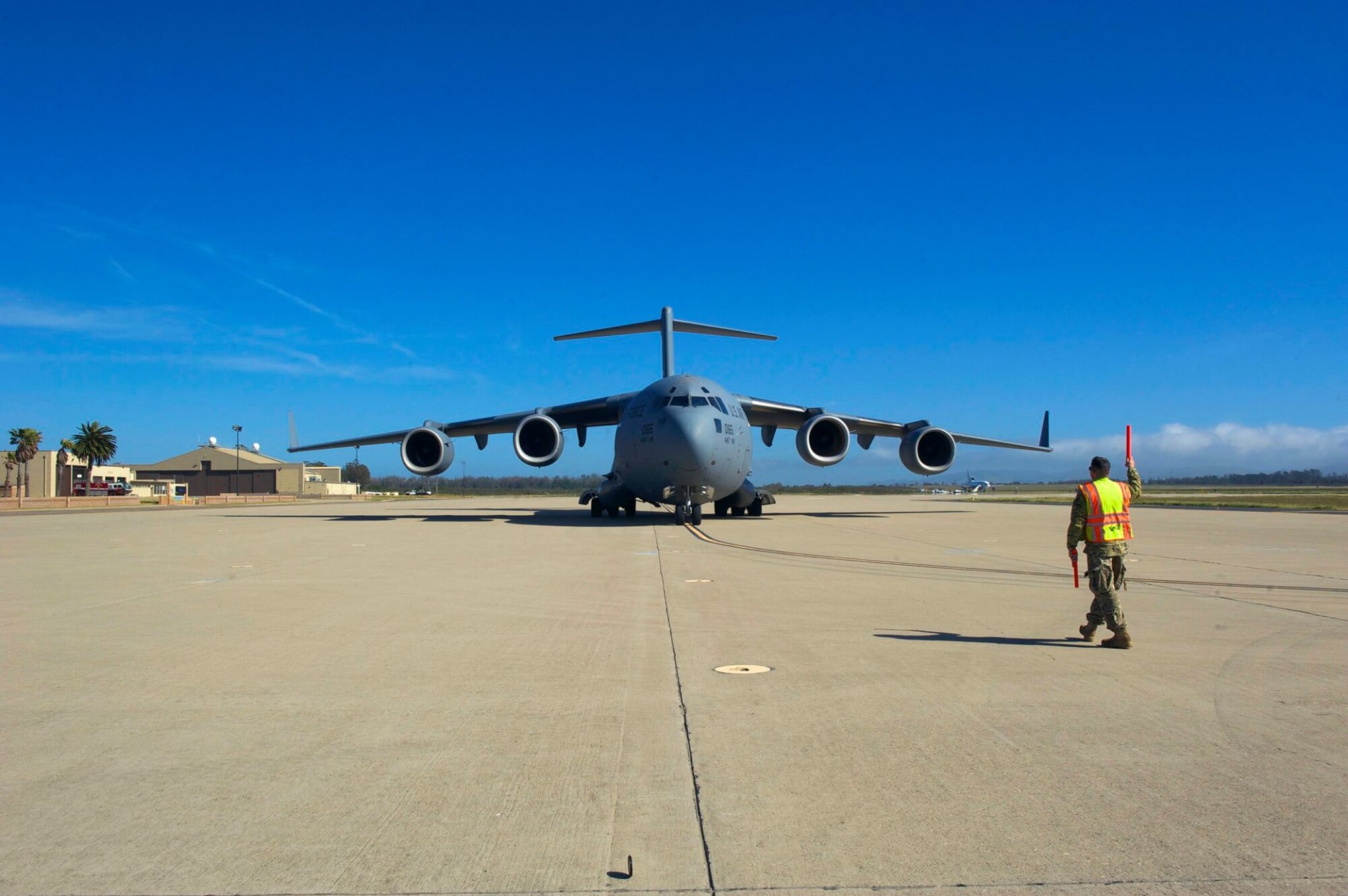 Master Sgt. Thomas Rowland, 439th Contingency Response Flight loadmaster, guides a C-17 Globemaster III, during a the Patriot Hook 2019 exercise, April 12, 2019 at Vandenberg Air Force Base, Calif. This particular air mobility exercise focused on the ability to rapidly deploy troops and cargo in the event of a humanitarian crisis. (U.S. Air Force photo by Staff Sgt. Shane Phipps)