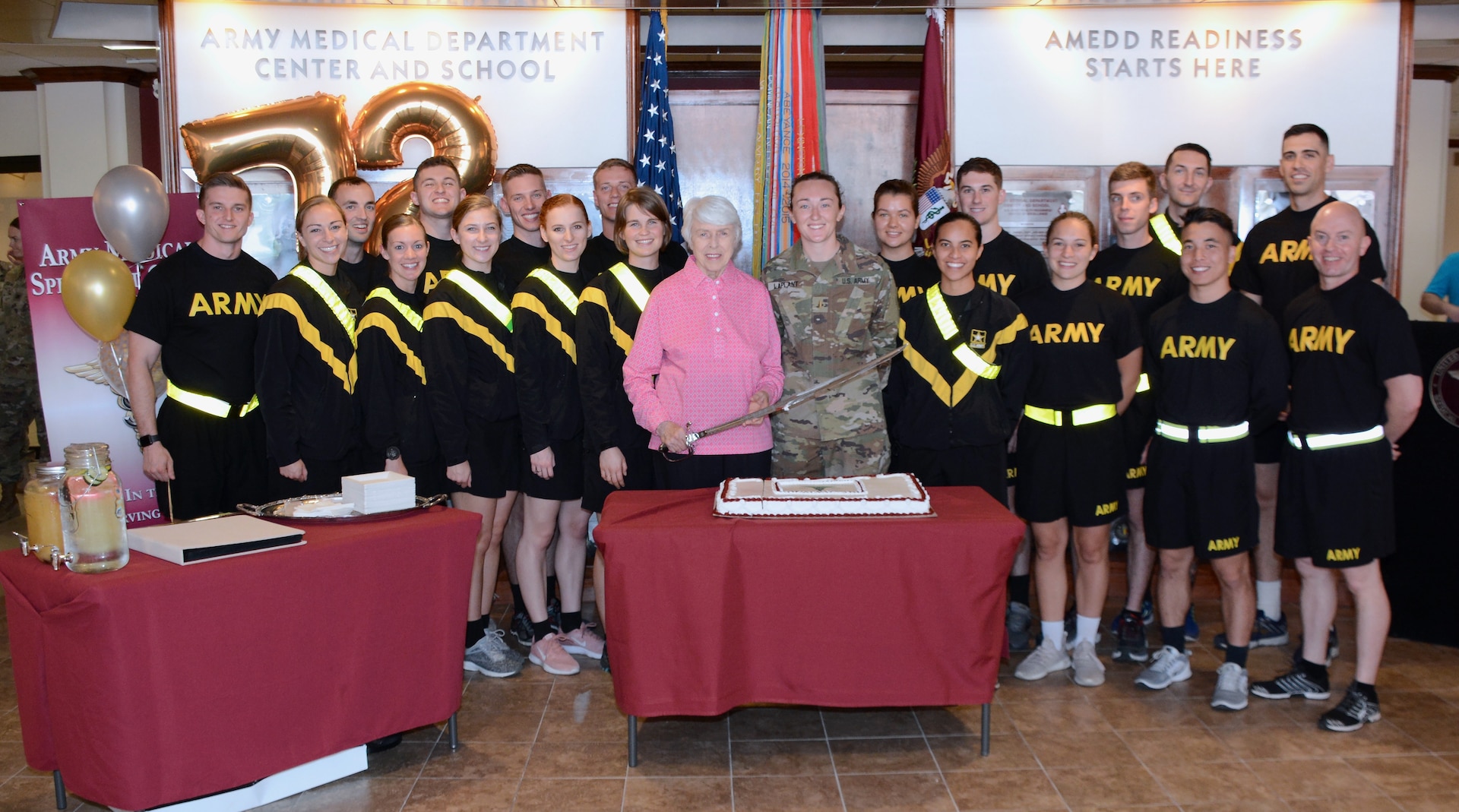 Retired Col. Jessie Breuer, 2nd Lt. Carley Laplant, and 19 of the newest members of the Army Medical Specialist Corps at the cake-cutting ceremony at the U.S. Army Medical Department Center and School, Health Readiness Center of Excellence, or AMEDDC&S HRCoE, headquarters building at Joint Base San Antonio-Fort Sam Houston April 16.
