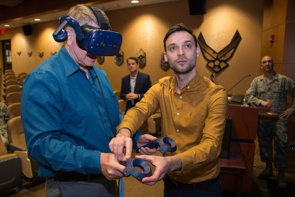 Jeffrey Fries, 1st Weather Group director of operations, learns to use virtual reality controllers from Dainius Slavinskas, technical director at Myriad Global Media, during a product handover March 14, 2019, at Offutt Air Force Base, Nebraska. 1st WXG fielded a virtual reality training product that will allow Air Force weather personnel to familiarize themselves with a tactical meteorological observation system, known as a TMQ-53. (U.S. Air Force photo by Paul Shirk)