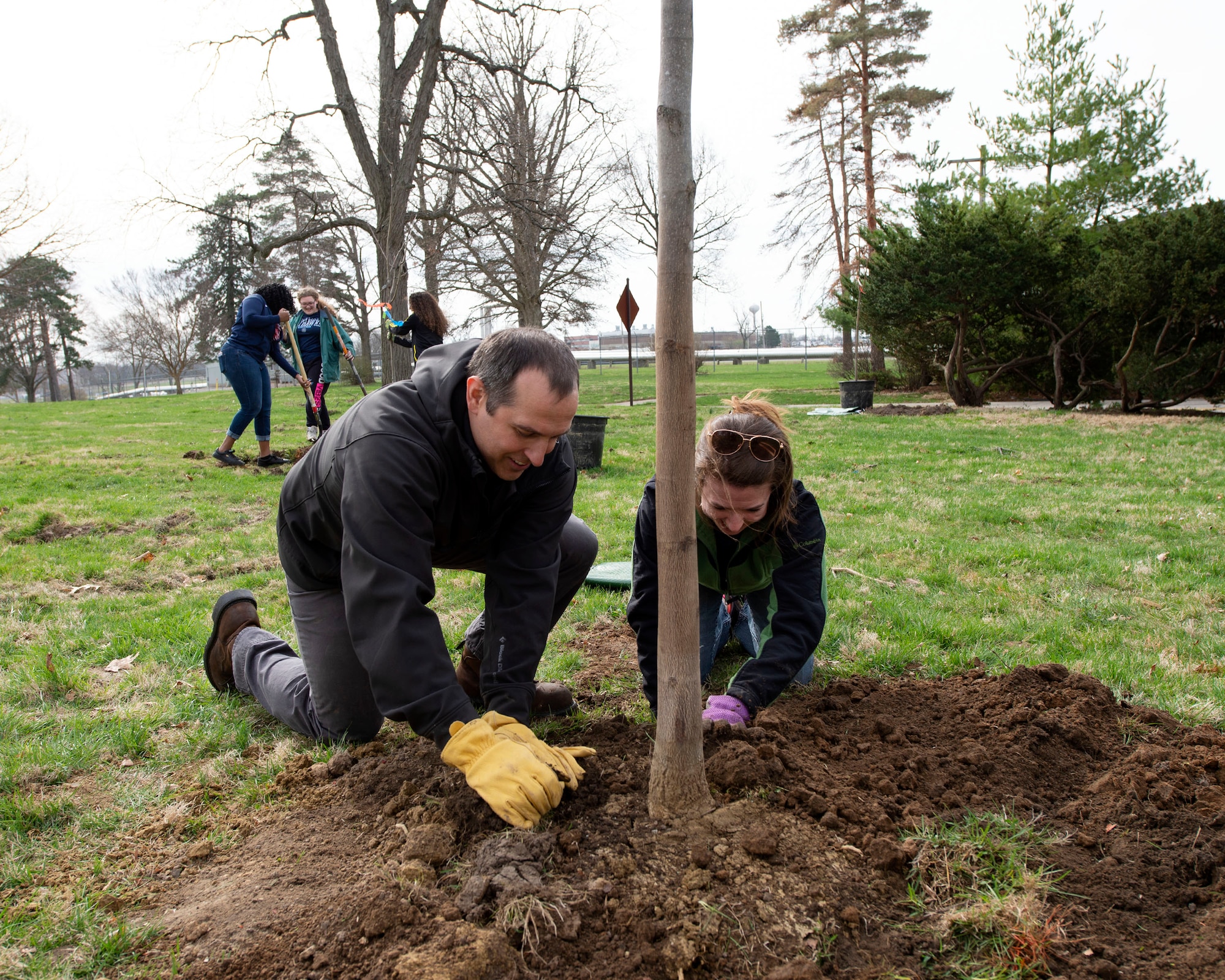 Michael Vaugh, (left) 88th Civil Engineering Group, hazardous waste program manager and Mandy Taylor, Fairborn High School environmental science teacher, pack dirt around a redbud tree as part of the 88th Civil Engineer Group and the National Park Service volunteer efforts for Arbor Day on the grounds near the Wright Brothers Memorial, Dayton, Ohio, April 11, 2019. Taylor’s advanced placement students planted a total of 26 trees in support of Arbor Day to protect trees and woodlands. (U.S. Air Force photo by Michelle Gigante)