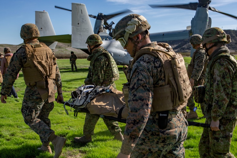 Troops walk carrying stretcher