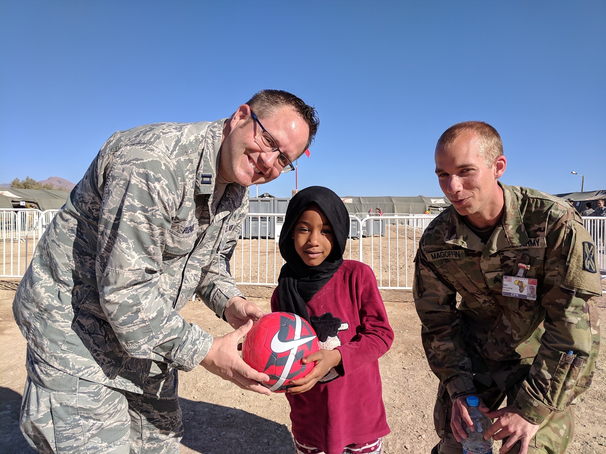 U.S. Air Force Capt. Matthew Plendl (left), 419th Medical Squadron, and U.S. Army Sgt. Wyatt Magoffin, Utah Army National Guard, present a soccer ball to a girl in Tata, Morocco