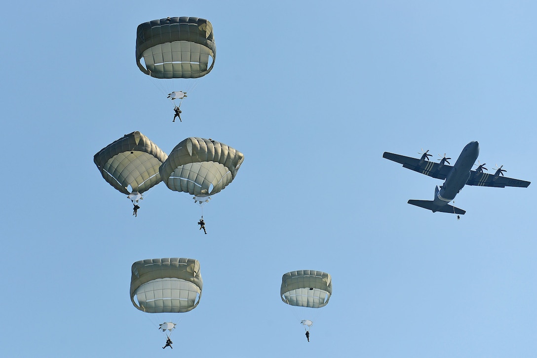 Five people parachute to the ground after jumping from an airplane.