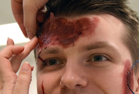 U.S. Air Force Senior Airman Marty Logston, 81st Surgical Operations Squadron medical technician, applies moulage on Staff Sgt. Oleg Lysenko, 81st Medical Support Squadron biomedical equipment technician, during a mass casualty and response exercise at the Elks Lodge in Biloxi, Mississippi, April 17, 2019. The scenario for the two-day event included a simulated plane crash with debris landing both on and off base in crowds of people. The exercise tested base and local civilian emergency response organizations' ability to operate in a multi-agency and multi-jurisdiction crisis situation. (U.S. Air Force photo by Kemberly Groue)
