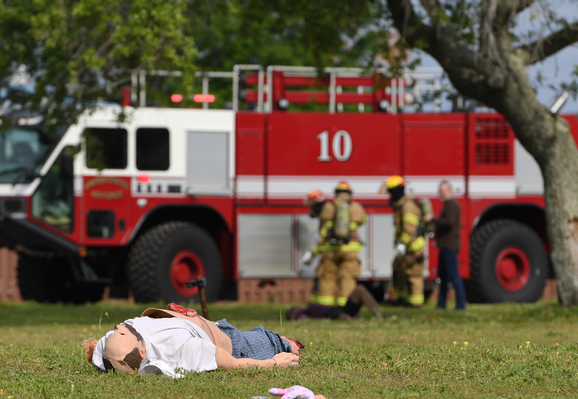 A mannequin portraying a "victim" lies on the ground as Keesler firefighters arrive on scene during a mass casualty and response exercise on Keesler Air Force Base, Mississippi, April 17, 2019. The scenario for the two-day event included a simulated plane crash with debris landing both on and off base in crowds of people. The exercise tested base and local civilian emergency response organizations' ability to operate in a multi-agency and multi-jurisdiction crisis situation. (U.S. Air Force photo by Kemberly Groue)