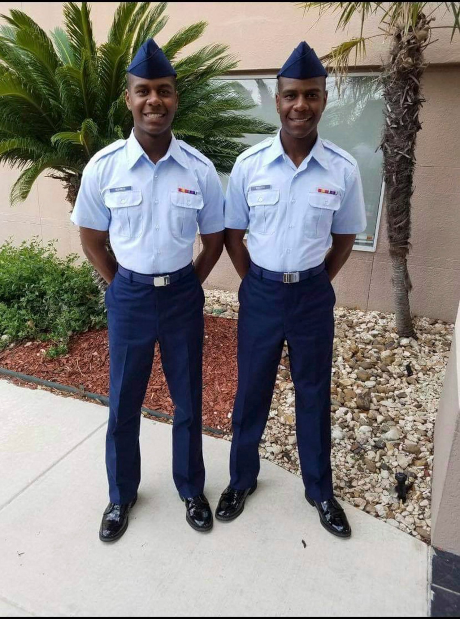 Two men standing together in front of a building.