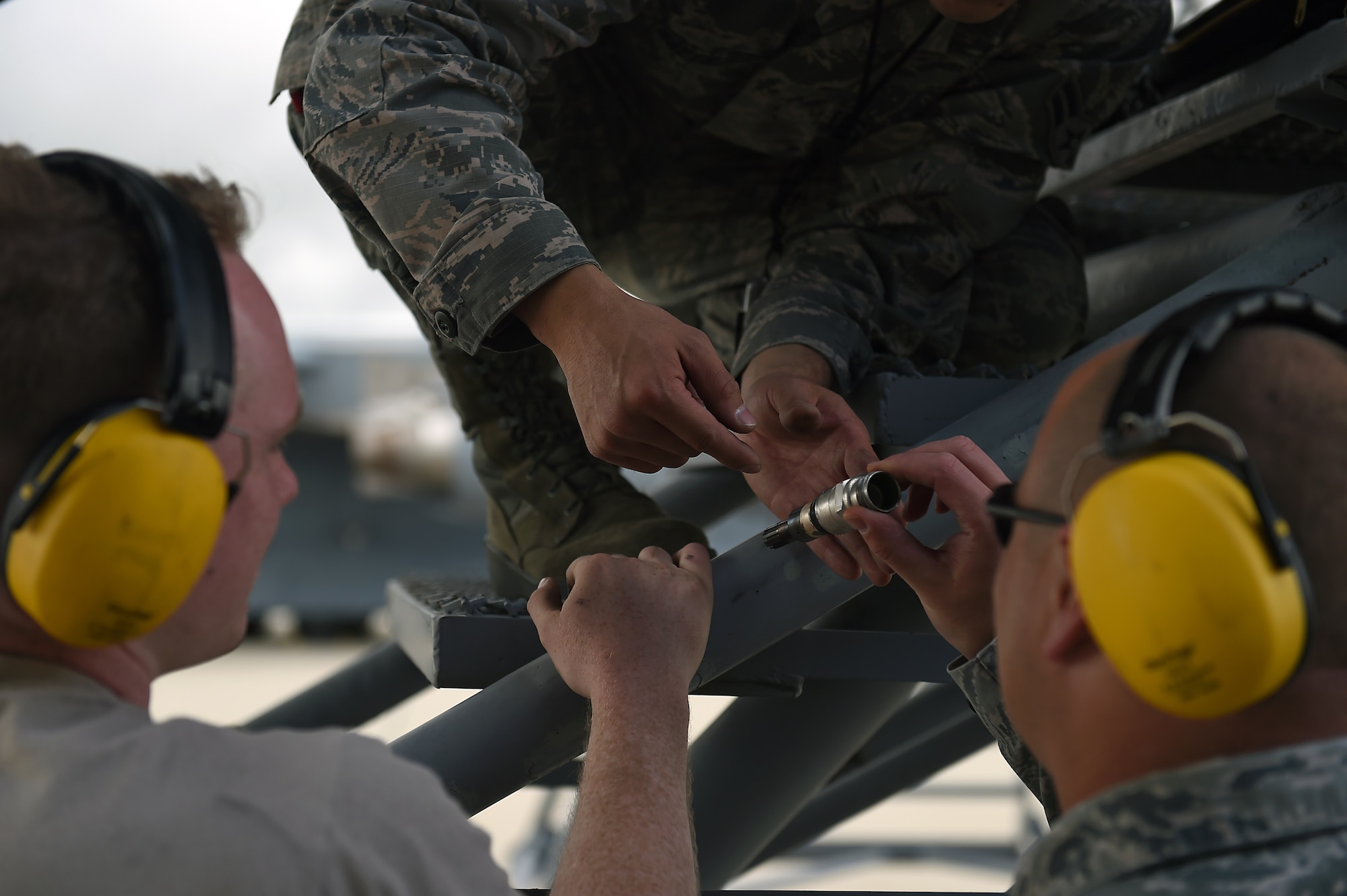 Airman 1st Class Brendan Watts, Airman 1st Class Ryan Watts, and Master Sgt. Jonathon Whitmer, 62nd Aircraft Maintenance Squadron crew chiefs, examine an igniter plug from the engine of a C-17 Globemaster III on March Air Reserve Base, California, April 3, 2019.