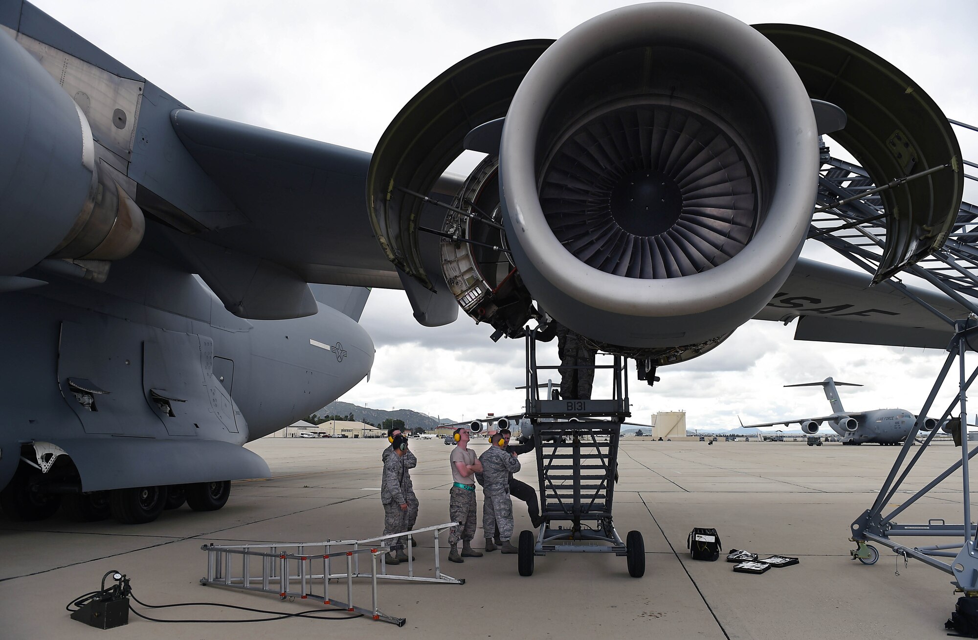 Several crew chiefs from the 62nd Aircraft Maintenance Squadron work to repair the engine of C-17 Globemaster III on March Air Reserve Base in California, April 3, 2019.