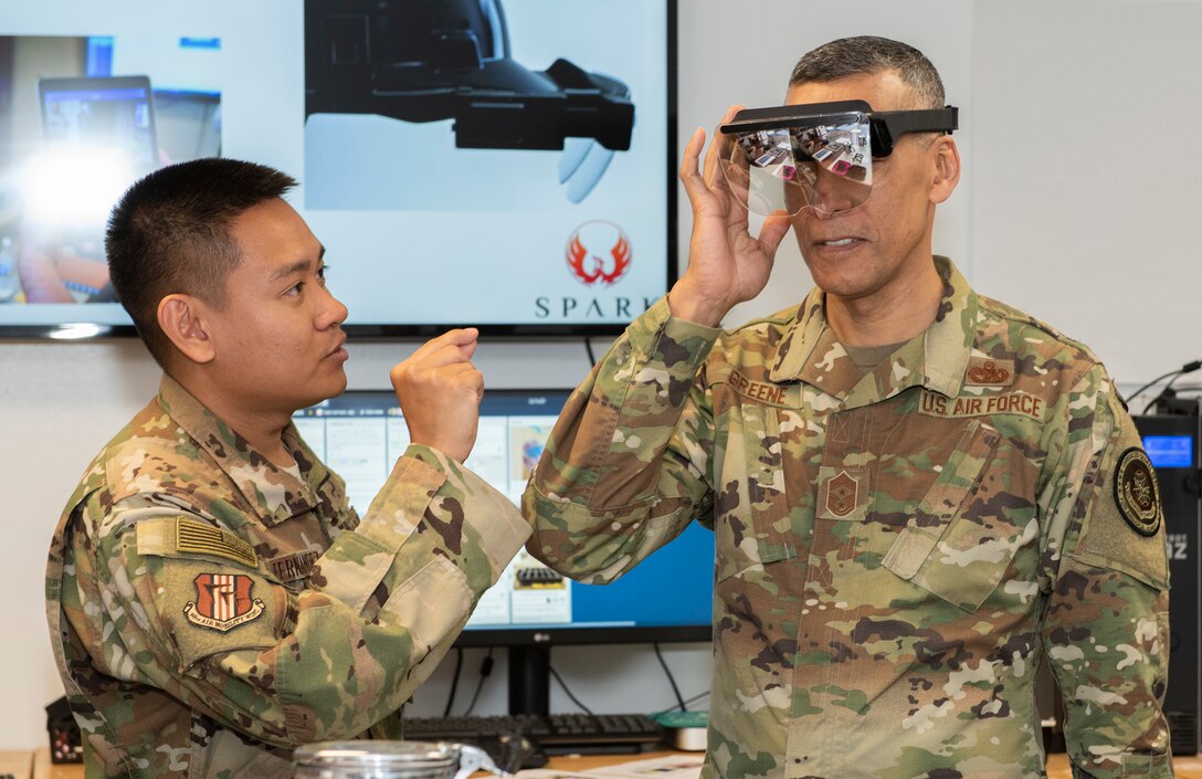 U.S. Air Force Chief Master Sgt. Terrence Greene, right, AMC command chief, tries out a pair of augmented reality glasses as
Capt. Kristofer Fernandez, deputy director, Phoenix Spark hub, explains their use during a visit to the Phoenix Spark innovation facility atTravis Air Force Base, California, April 16, 2019. During the four-day base tour Greene and Gen. Maryanne Miller, AMC commander, met with
Airmen across Travis to see how the base enhances AMC’s global mobility capabilities. (U.S. Air Force photo by Heide Couch)