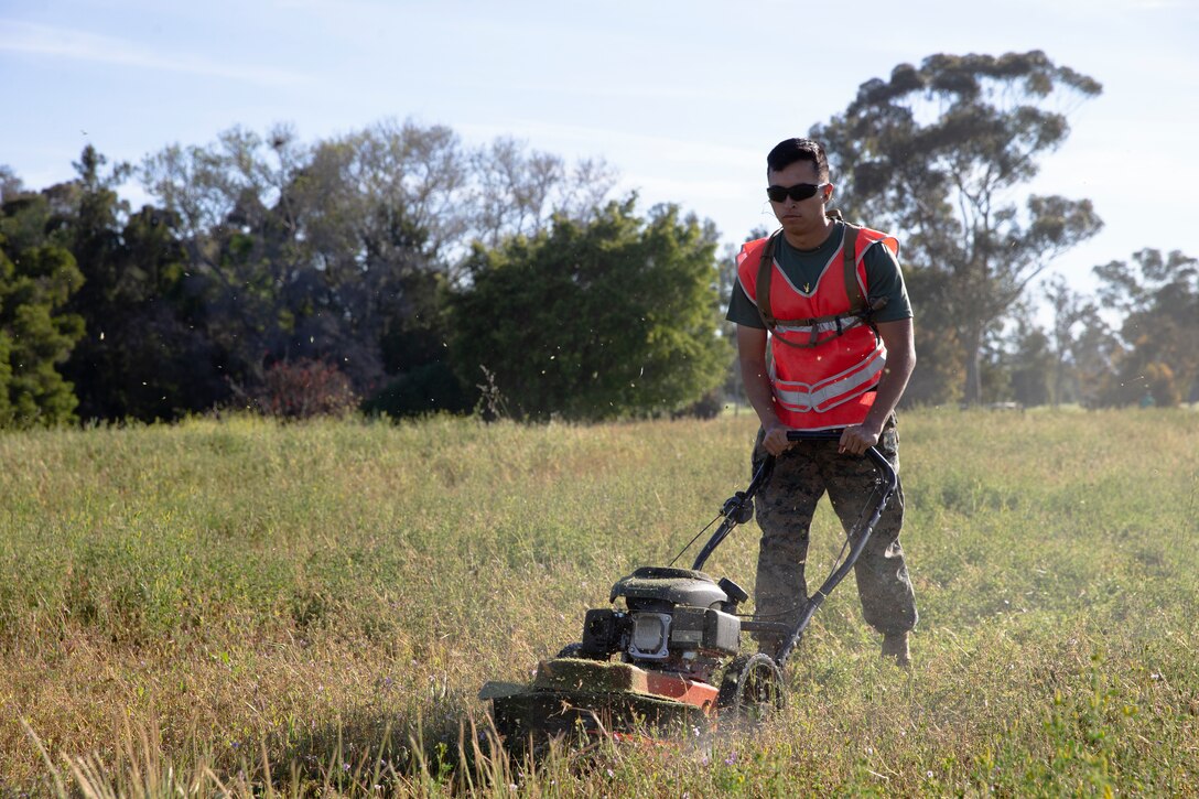Pfc. Brian Flores, administrative clerk with Headquarters and Headquarters Squadron, cuts grass during base clean up at Marine Corps Air Station Miramar, Calif., April 11. Base-wide cleanups are conducted on and off the installation to promote the installations high standards and a cleaner environment. (Photo by Cpl. Preston Hightower)