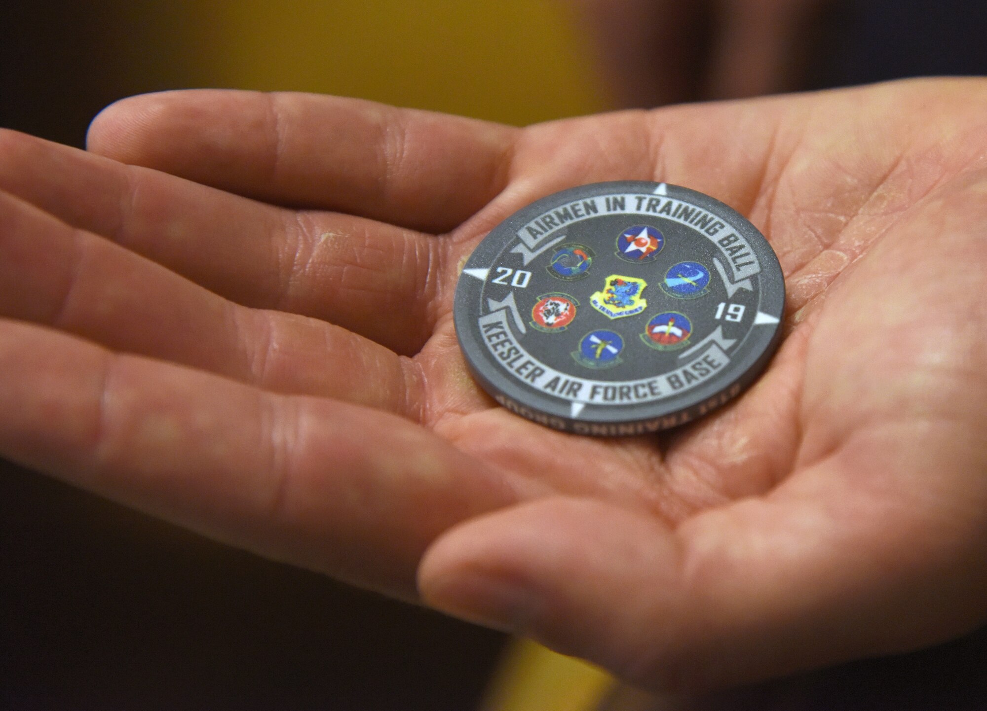 U.S. Air Force Tech. Sgt. Zachary Bartlett, 81st Training Group Airman transition assistance flight flight chief, displays a chip commemorating the Airmen In Training Ball at the Bay Breeze Event Center on Keesler Air Force Base, Mississippi, April 19, 2019. The event, hosted by the 81st TRG, is the first of its kind and was geared toward training Airmen on how to participate and act during a formal military ball so they can feel confident in their abilities when arriving at their follow-on locations. The Airmen served in key positions throughout the ball such as emcees, color guard, POW/MIA table ceremony, national anthem singer and the invocation. (U.S. Air Force photo by Kemberly Groue)