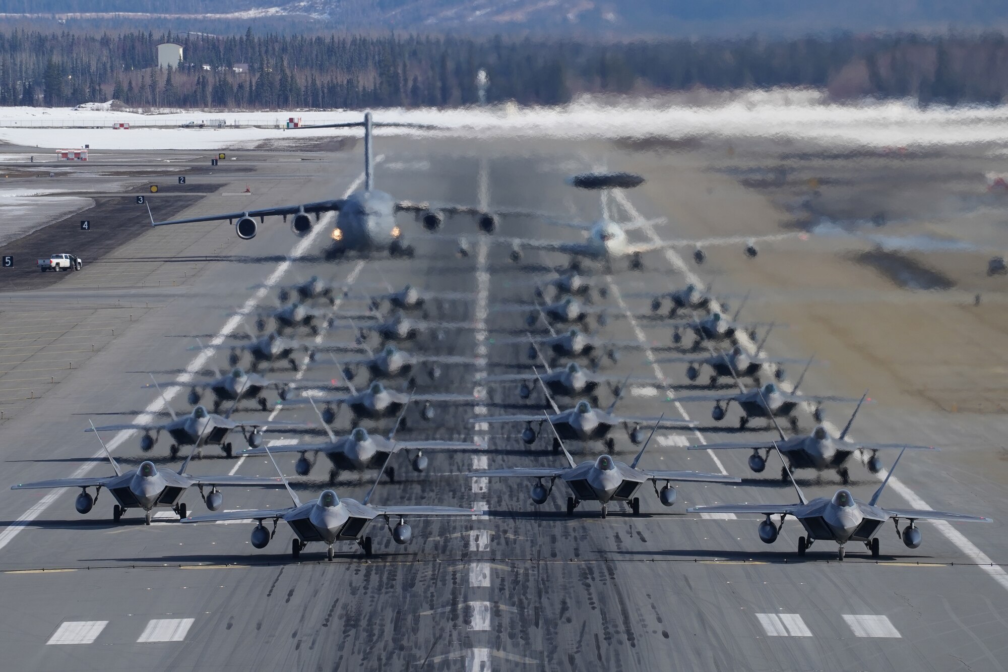 Twenty-four F-22 Raptors from 3rd Wing and 477th Fighter Group, a C-17 Globemaster III and an E-3 Sentry participate in a close formation taxi, known as an Elephant Walk, March 26, 2019, during a Polar Force exercise at Joint Base Elmendorf-Richardson, Alaska. This two-week exercise gives squadrons an opportunity to demonstrate their abilities to forward deploy and deliver overwhelming combat power. (U.S. Air Force photo/Justin Connaher)