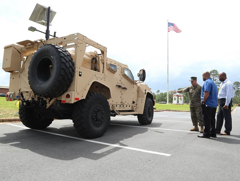 A Marine and civilian-Marines discuss the capabilities of the Joint Light Tactical Vehicle, which will take place of the Humvee, during a roadshow in front of Marine Corps Logistics Command Headquarters, April 9.