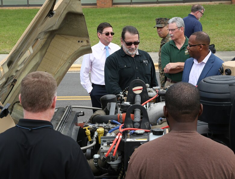 Marines and civilian-Marines look under the hood at the engine of the Joint Light Tactical Vehicle during a roadshow in front of Marine Corps Logistics Command Headquarters, April 9.