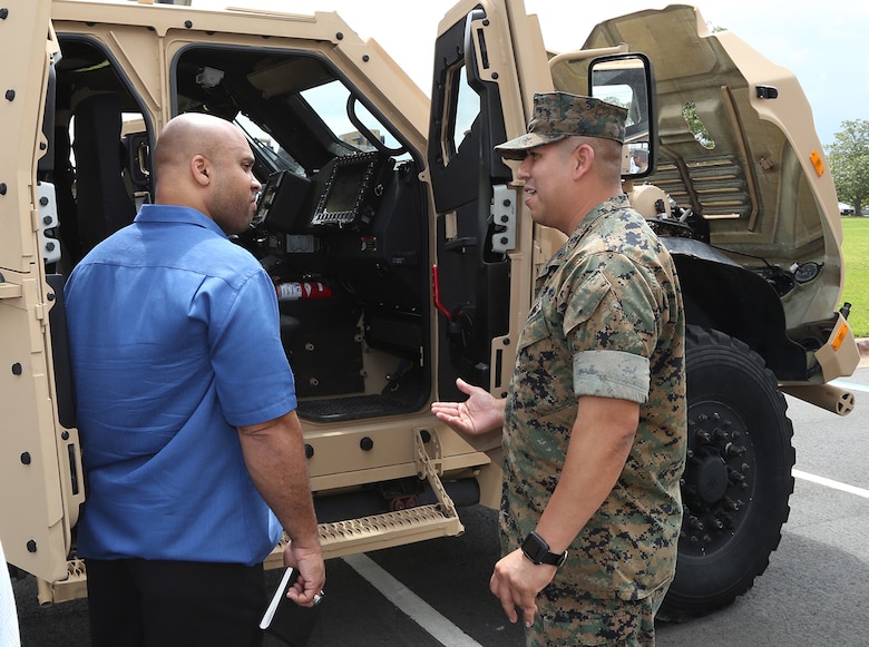 A Marine and civilian-Marine discuss the capabilities of the Joint Light Tactical Vehicle, which will take place of the Humvee, during a roadshow in front of Marine Corps Logistics Command Headquarters, April 9.