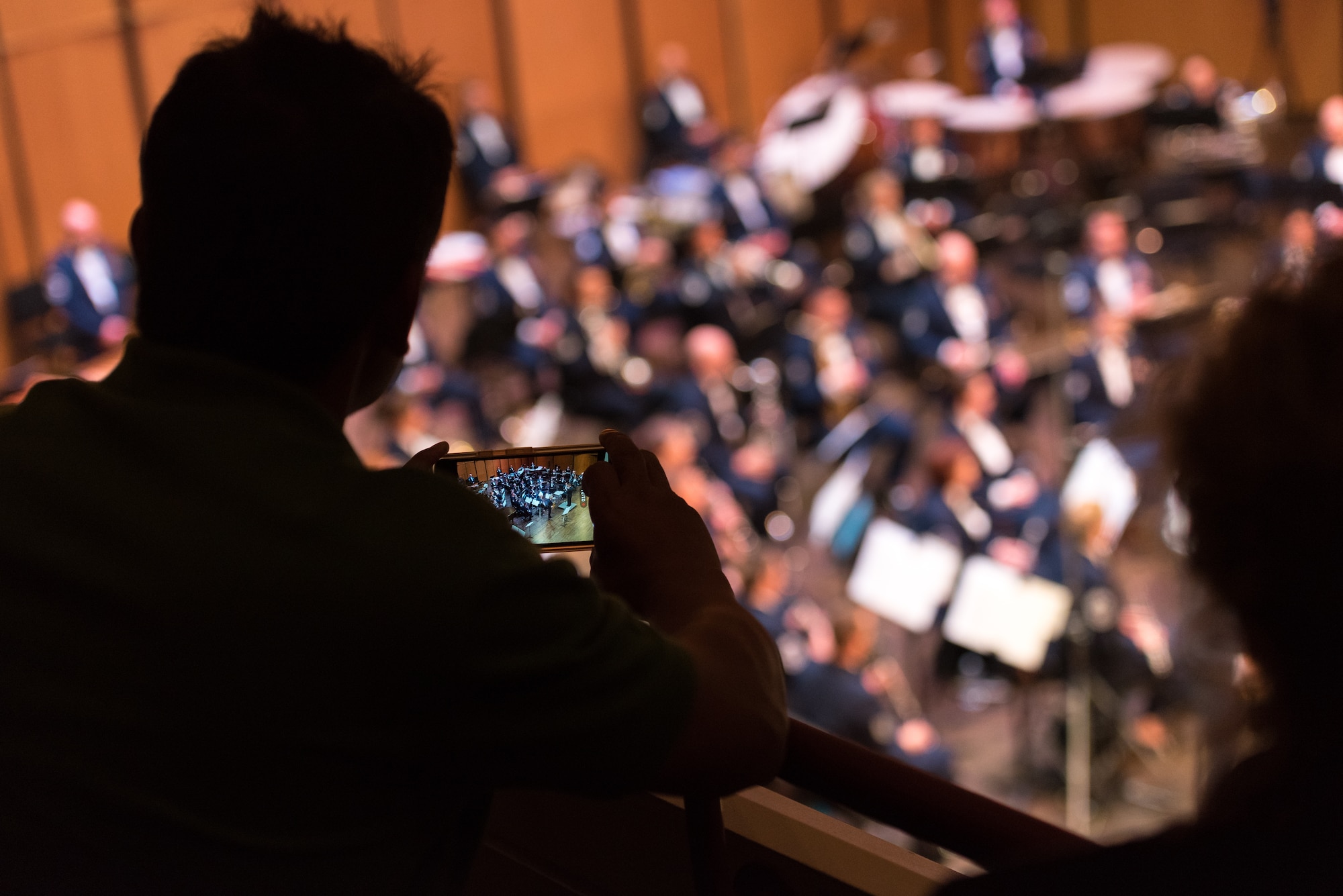 An audience member snaps a picture of the Concert Band on Apr. 18, during the final concert of The U.S. Air Force Band's 2019 Guest Artist Series. The concert featured internationally acclaimed saxophonist Joe Lulloff. (U.S. Air Force photo by Master Sgt. Grant Langford)