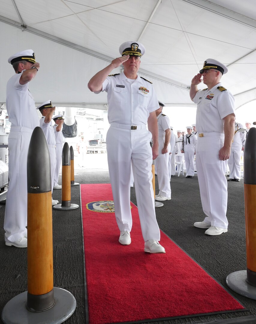 An Indian Navy sailor adjusts his colleague's uniform prior to the