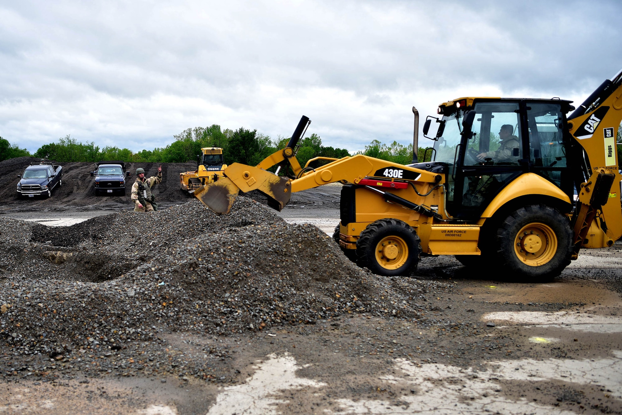 A large piece of yellow machinery grabs dirt from a hole in the ground.