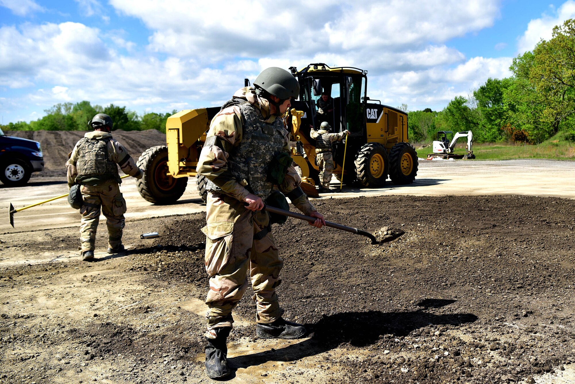 Three men shovel dirt into a hole in the ground.