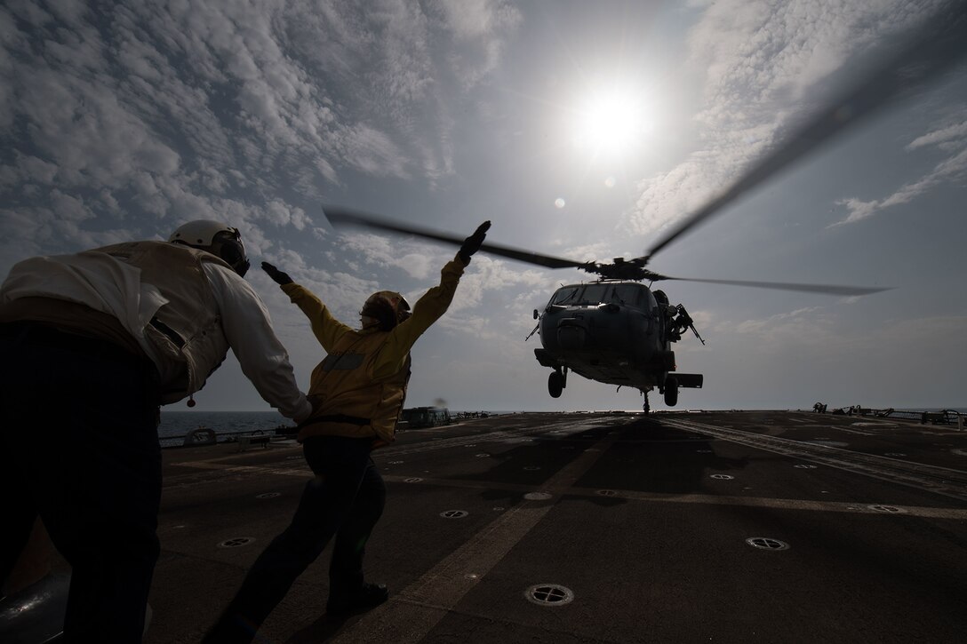 A sailor directs an aircraft during a landing.