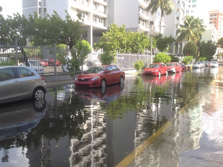 flooded street with cars and a building on the left