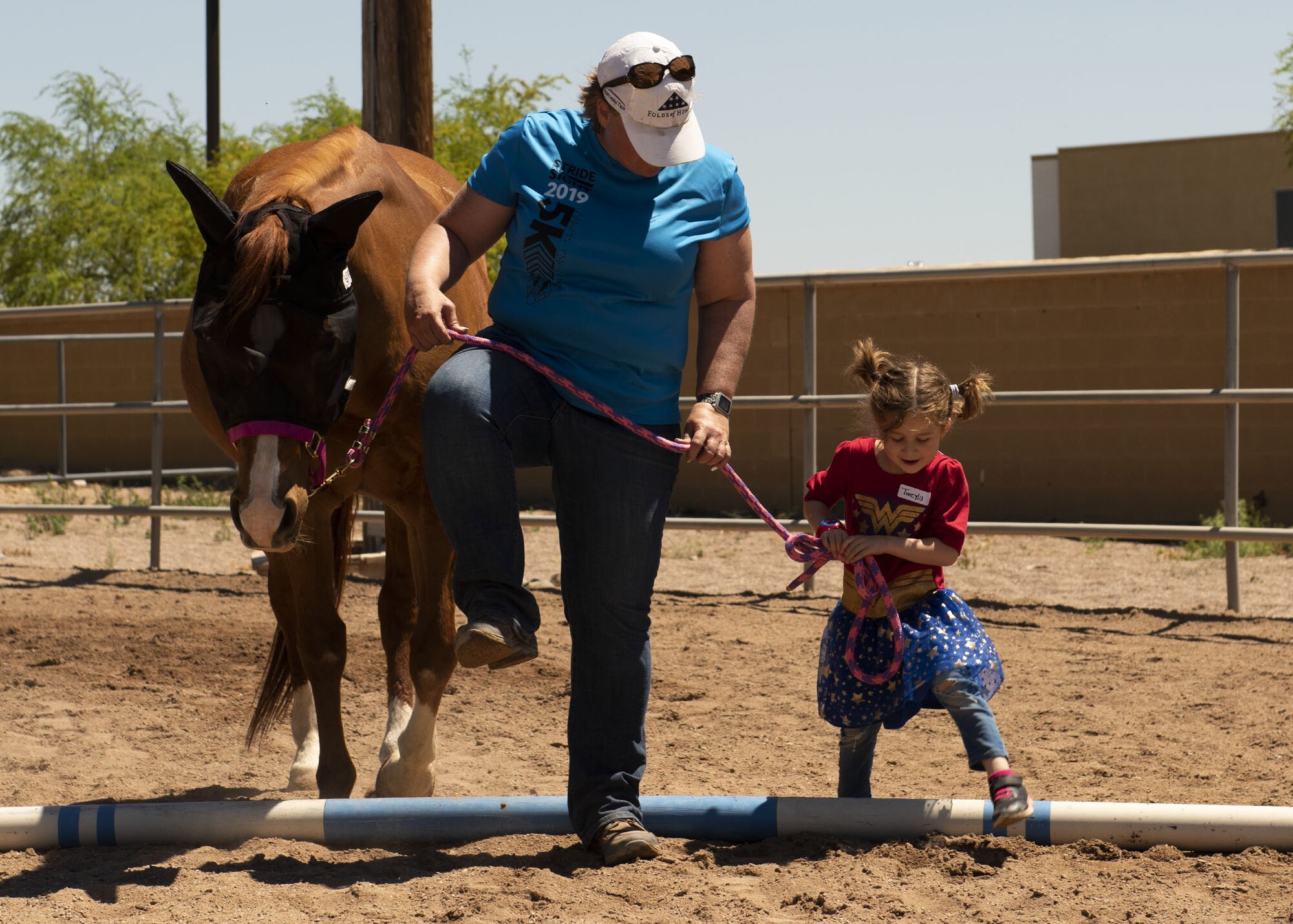 A volunteer and a child from Luke Air Force Base’s Exceptional Family Member Program lead a horse over an obstacle at Horses Help, April 20, 2019, in Phoenix, Ariz.