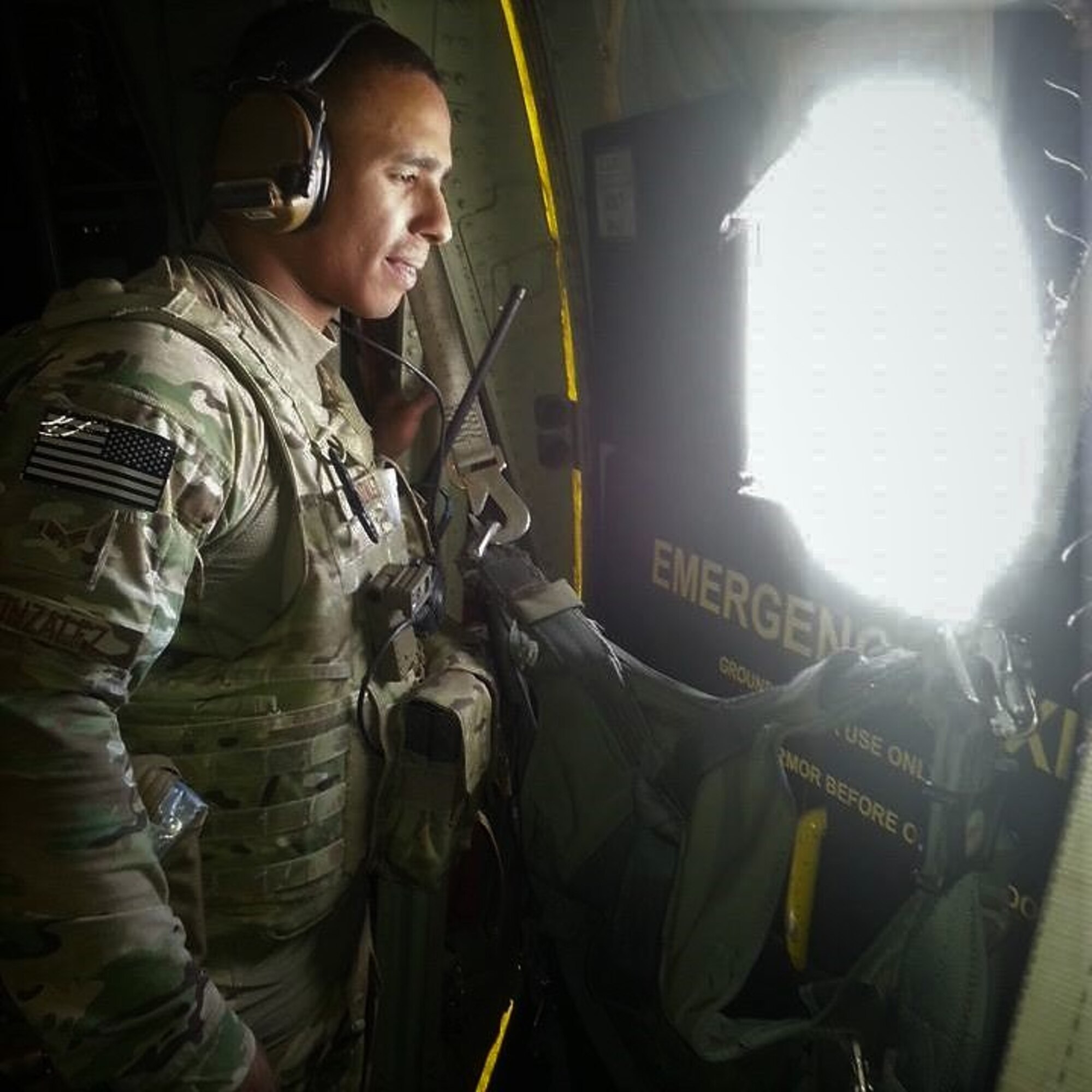 Tech. Sgt. Carlos Gonzalez looks out a while aboard a C-130 Hercules aircraft while deployed in 2016.