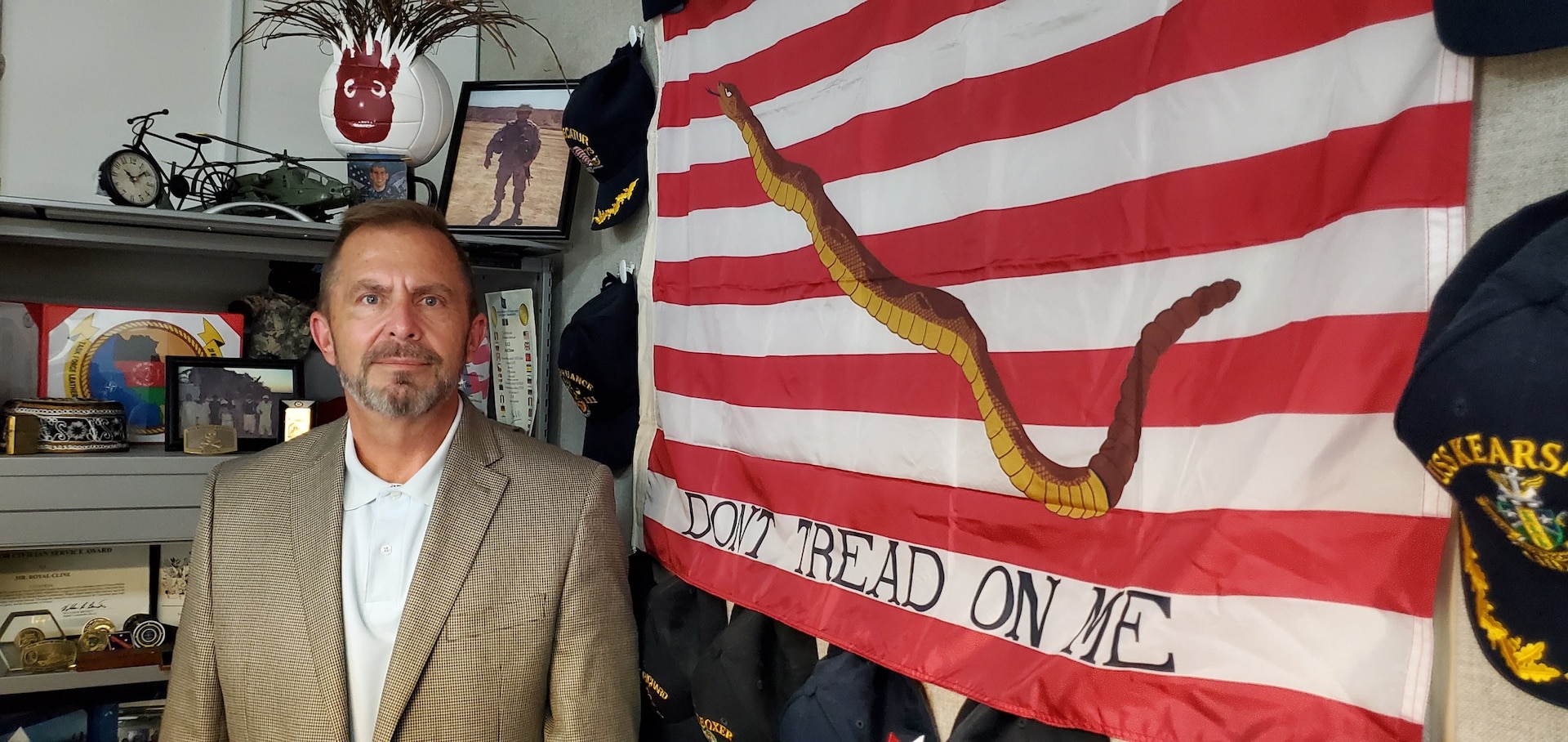 Man stands in office next to First Navy Jack flag.
