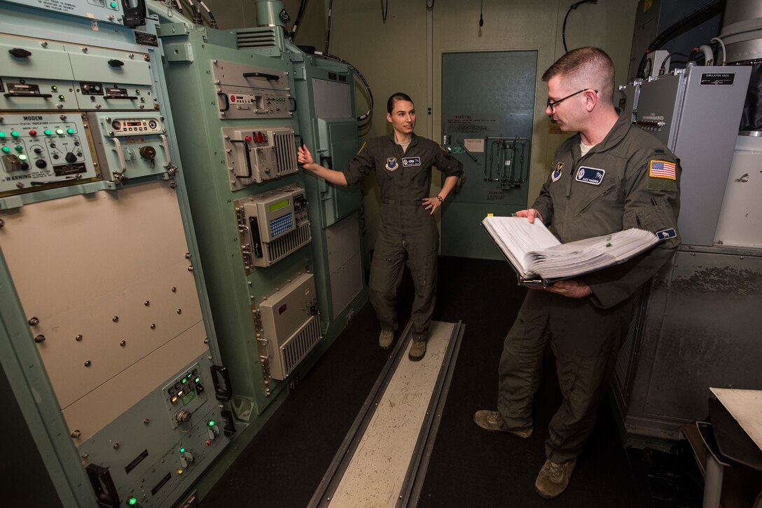 Airmen stand beside large network devices