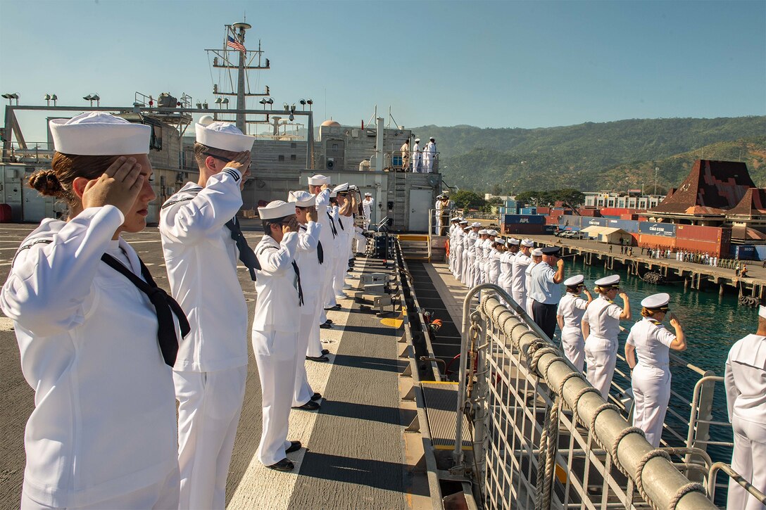 Sailors salute while arriving in East Timor on a ship.