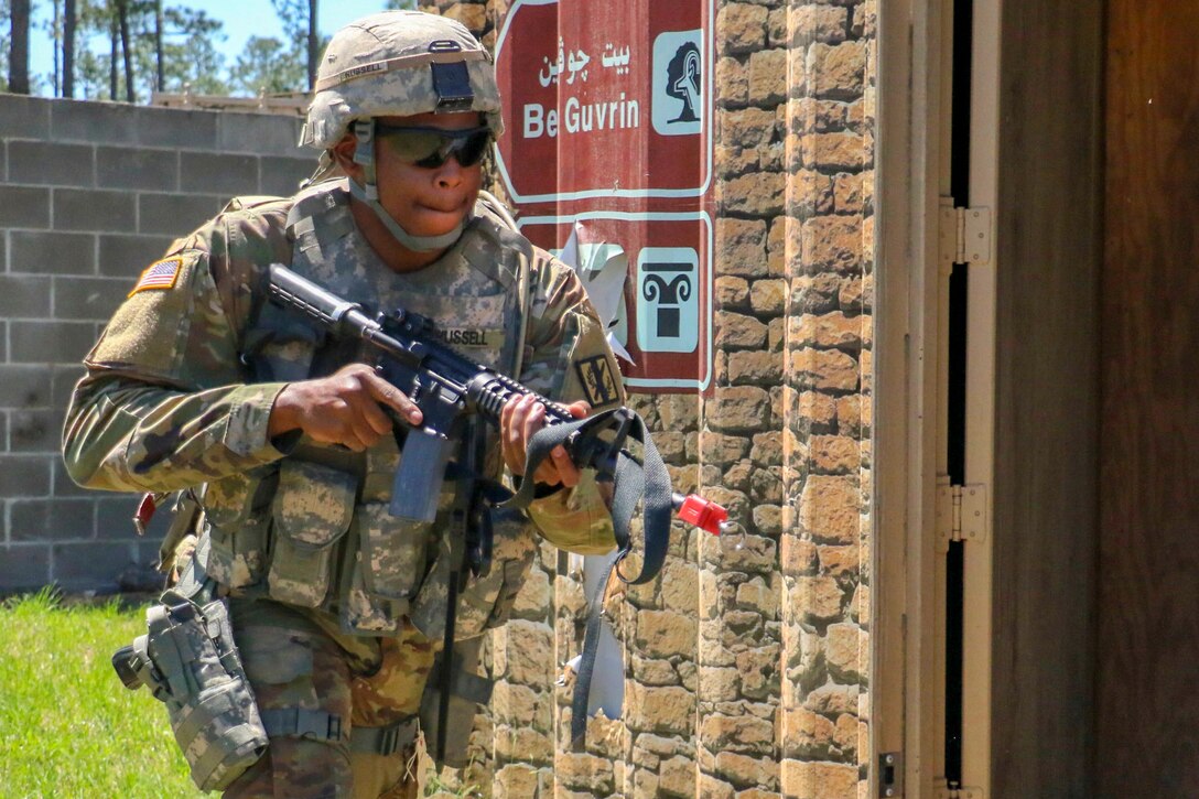 A guardsman holds a rifle as he enters the doorway to a building.