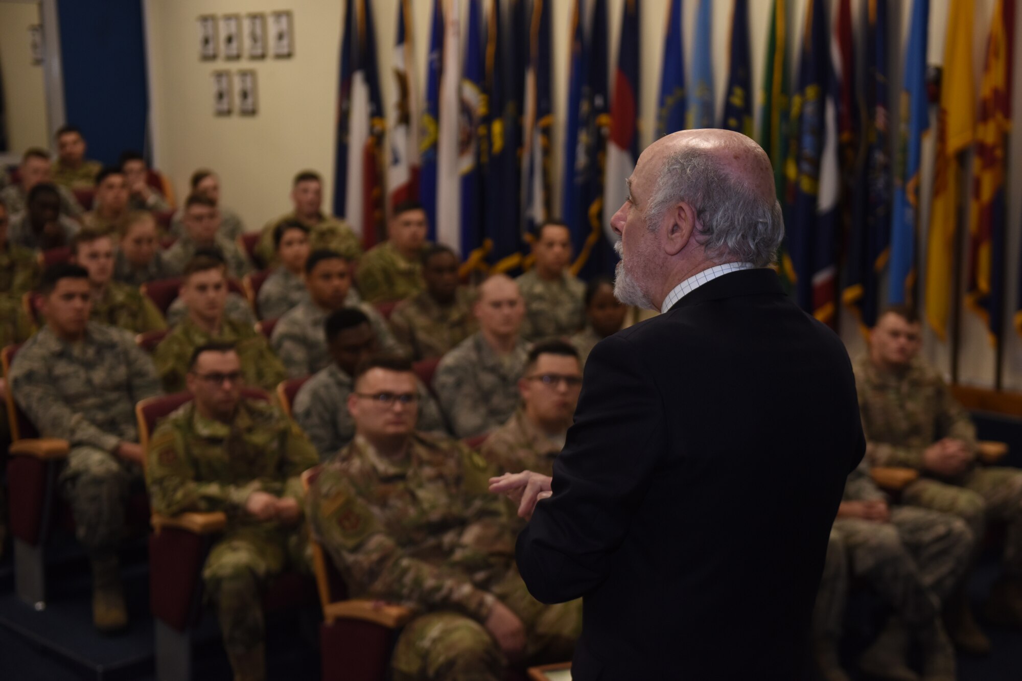 Peter Walmsley, 48th Security Forces Squadron honorary commander, speaks to an Airman Leadership School class at Royal Air Force Feltwell, England, April 16, 2019. Walmsley presented his father’s medals, along with his flying jacket and some other pictures and tokens that represent his father for the students. (U.S. Air Force photo by Airman 1st Class Madeline Herzog)