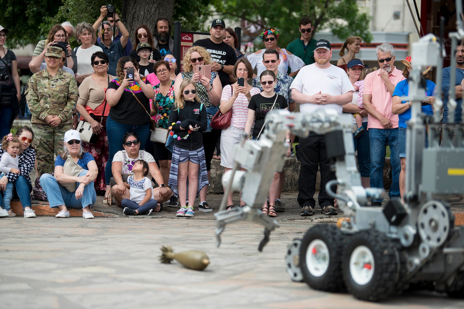 The Air Force Day at the Alamo audience watches a robot operated by the 502nd Civil Engineer Squadron, Explosive Ordnance Disposal, reach for a inert munition during an equipment and methods for bomb detection and disposal demonstration during San Antonio’s Fiesta Air Force Day at the Alamo, April 22, 2019. From its beginning in 1891, Fiesta has grown into an annual celebration that includes civic and military observances, street and river parades, exhibits, pilgrimages and memorials.