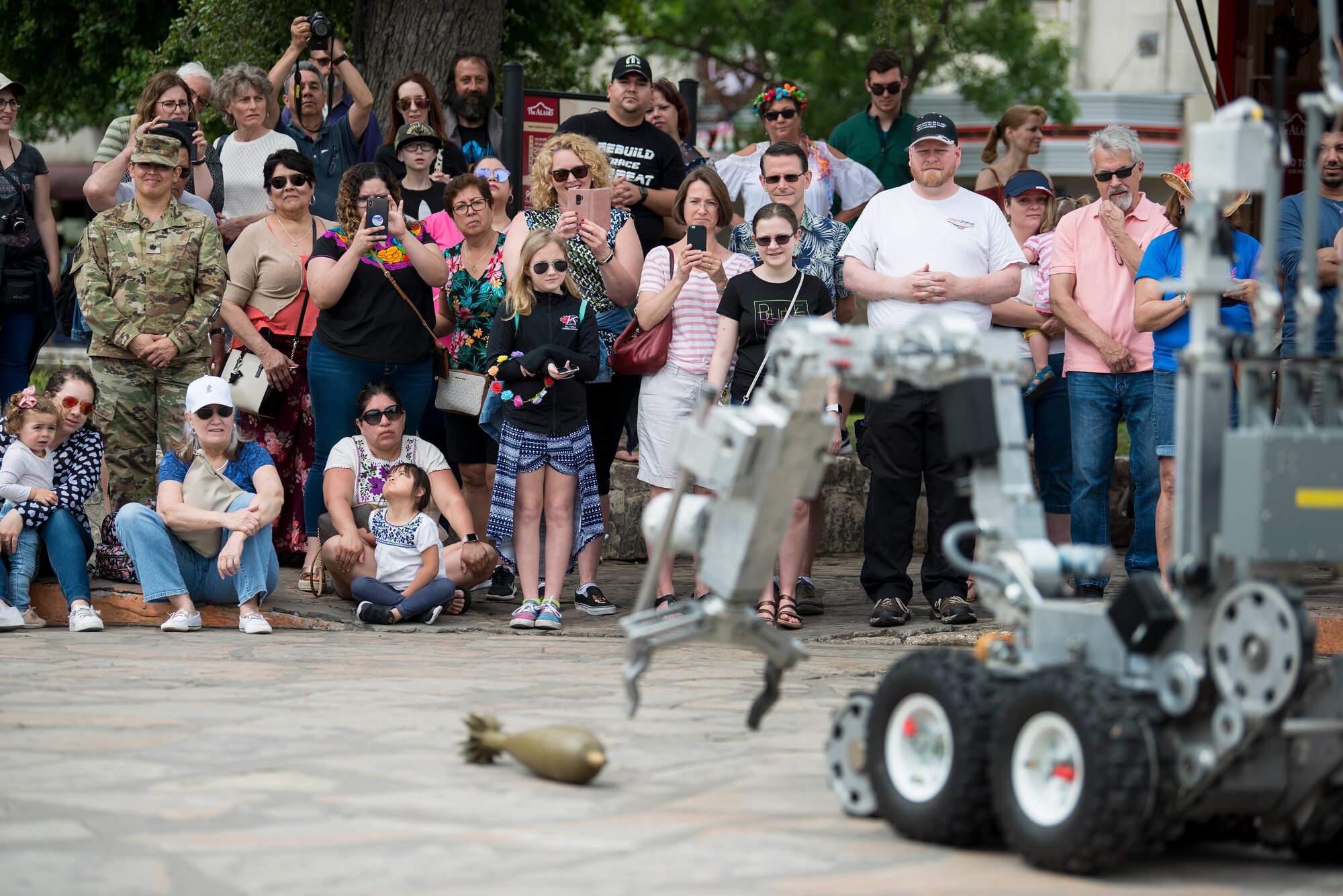 The Air Force Day at the Alamo audience watches a robot operated by the 502nd Civil Engineer Squadron, Explosive Ordnance Disposal, reach for a inert munition during an equipment and methods for bomb detection and disposal demonstration during San Antonio’s Fiesta Air Force Day at the Alamo, April 22, 2019. From its beginning in 1891, Fiesta has grown into an annual celebration that includes civic and military observances, street and river parades, exhibits, pilgrimages and memorials.