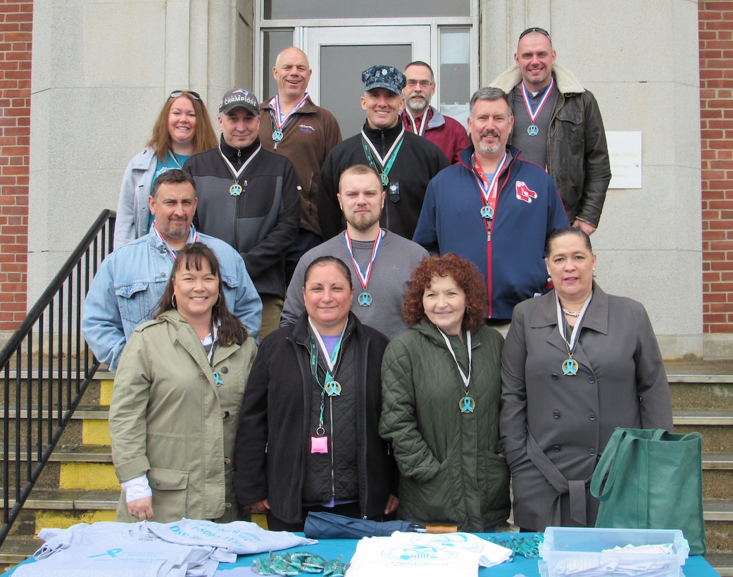 Group photo behind table of t-shirts and promotional items.