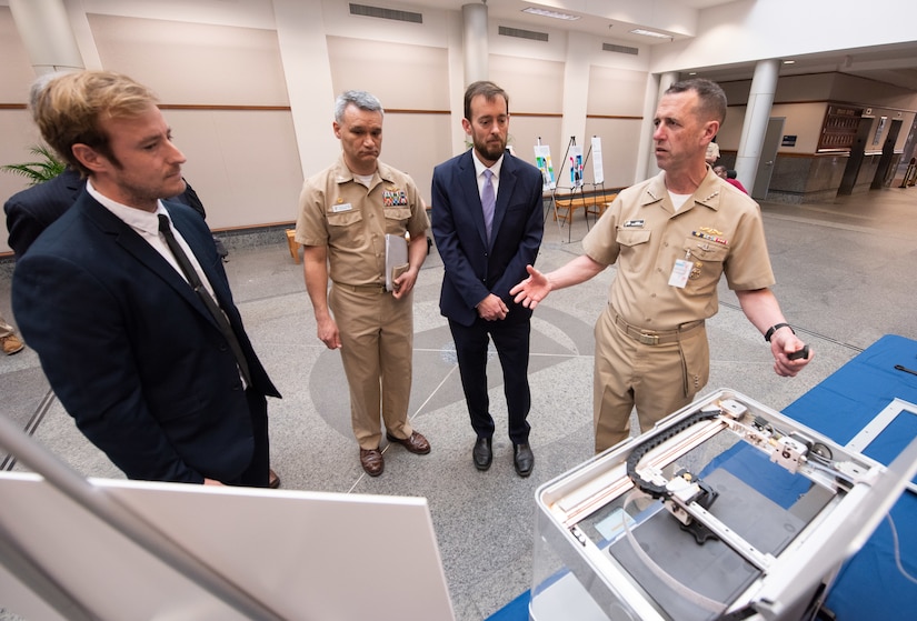Chief of Naval Operations Adm. John Richardson, right, chats with Naval Information Warfare Center Atlantic’s Josh Heller, left, about using 3D printing to enable rapid solutions to materiel problems, as NIWC Atlantic Commanding Officer Capt. Wesley Sanders and Executive Officer Christopher Miller look on.