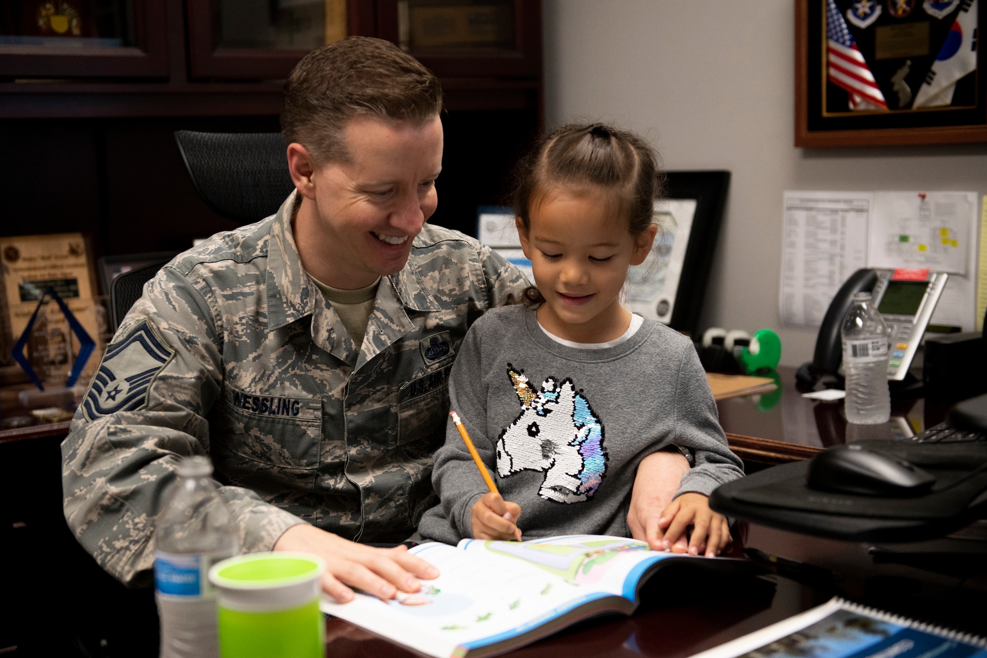 U.S. Air Force Senior Master Sgt. Joshua Wessling, 33rd Fighter Wing wing staff superintendent, helps his daughter practice her writing and reading skills in his office Apr. 25, 2019, at Eglin Air Force Base, Florida. April 25th is "National Take Our Sons and Daughters to Work Day" and Wessling decided to show his son and daughter his daily life at work. (U.S. Air Force Photo by Senior Airman Cassidy Woody)
