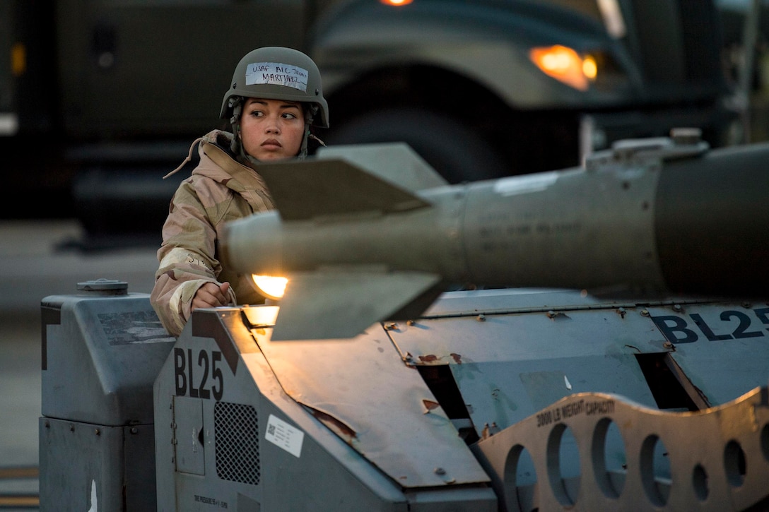 An airman drives a military vehicle with a large ammunition on top.