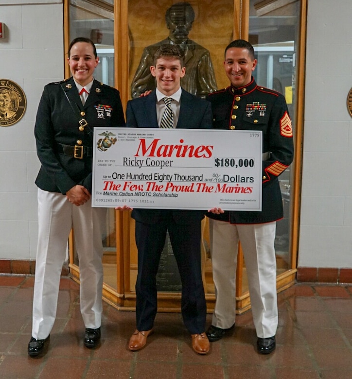 U.S. Marines with Marine Corps Recruiting Station Tampa present a check for the Marine Corps Naval Reserve Officer Training Corps Scholarship to Ricky Cooper, a native of Tampa, Florida, at Plant High School in Tampa, Florida, April 24, 2019.