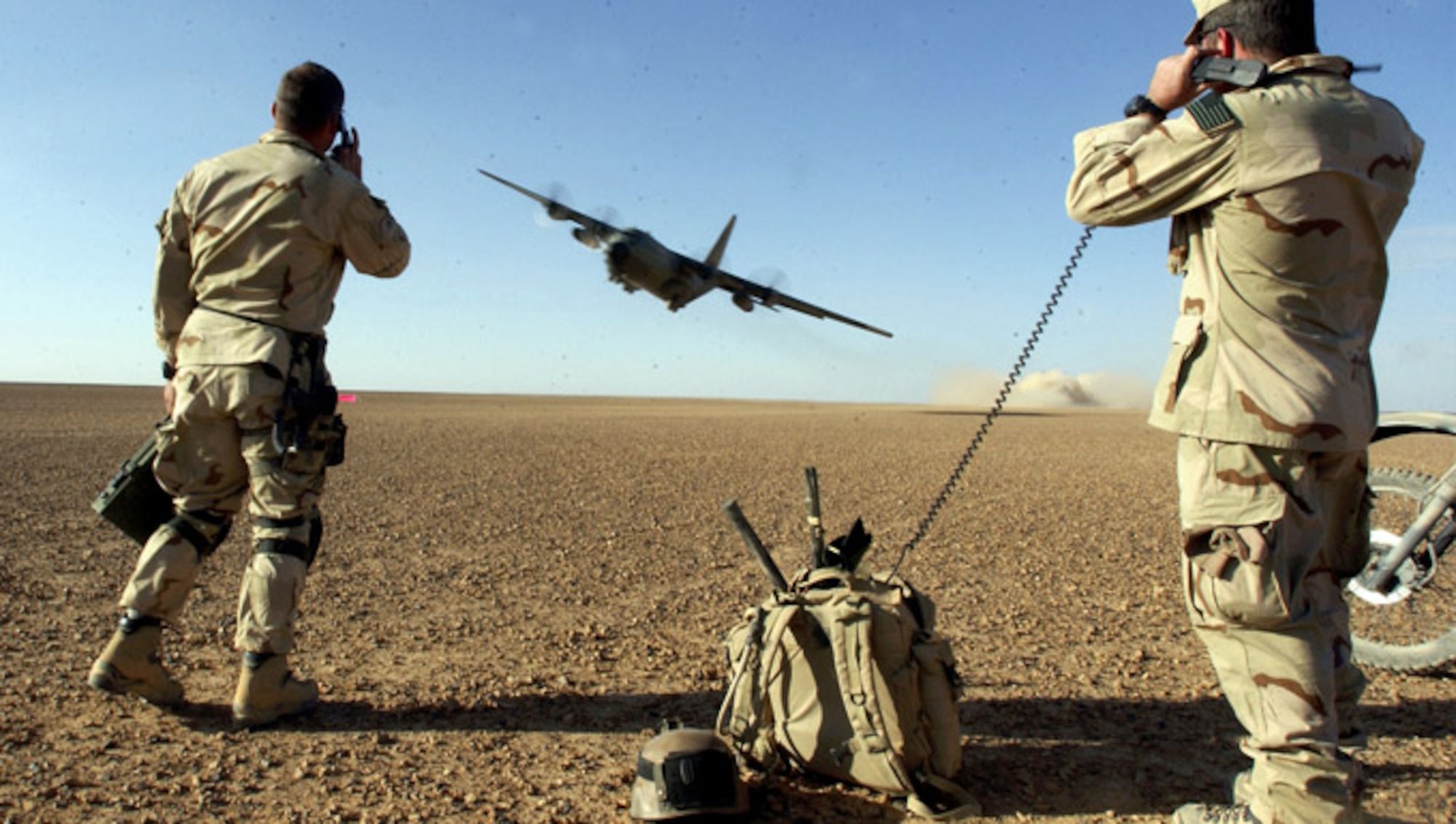 Two special operations officers watching a plane land.
