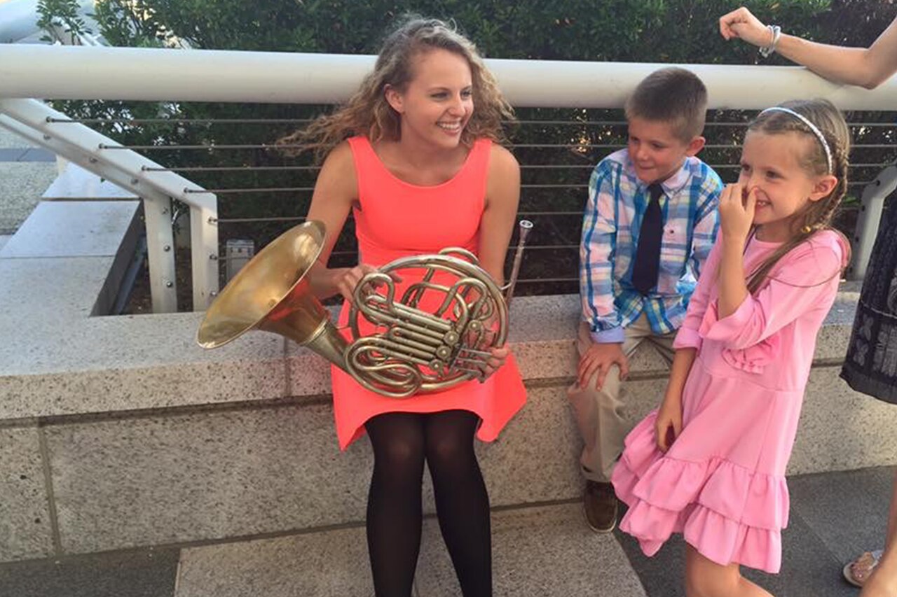 Woman with French horn interacts with children.