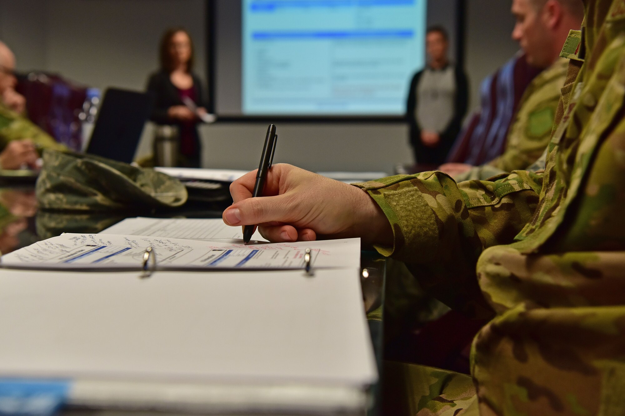 Air Force Colonel takes down notes from a spark tank presentation.