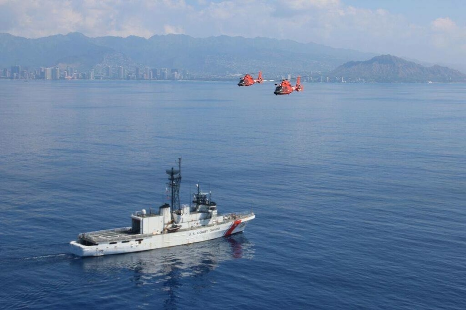 USCGC Alex Haley (WMEC 39) steams offshore of Honolulu as two MH-65 Dolphin helicopters from Coast Guard Air Station Barbers Point pass overhead March 4, 2016. The Alex Haley crew is in Hawaii for tailored ships training availability to assess the crew and the ship's readiness.