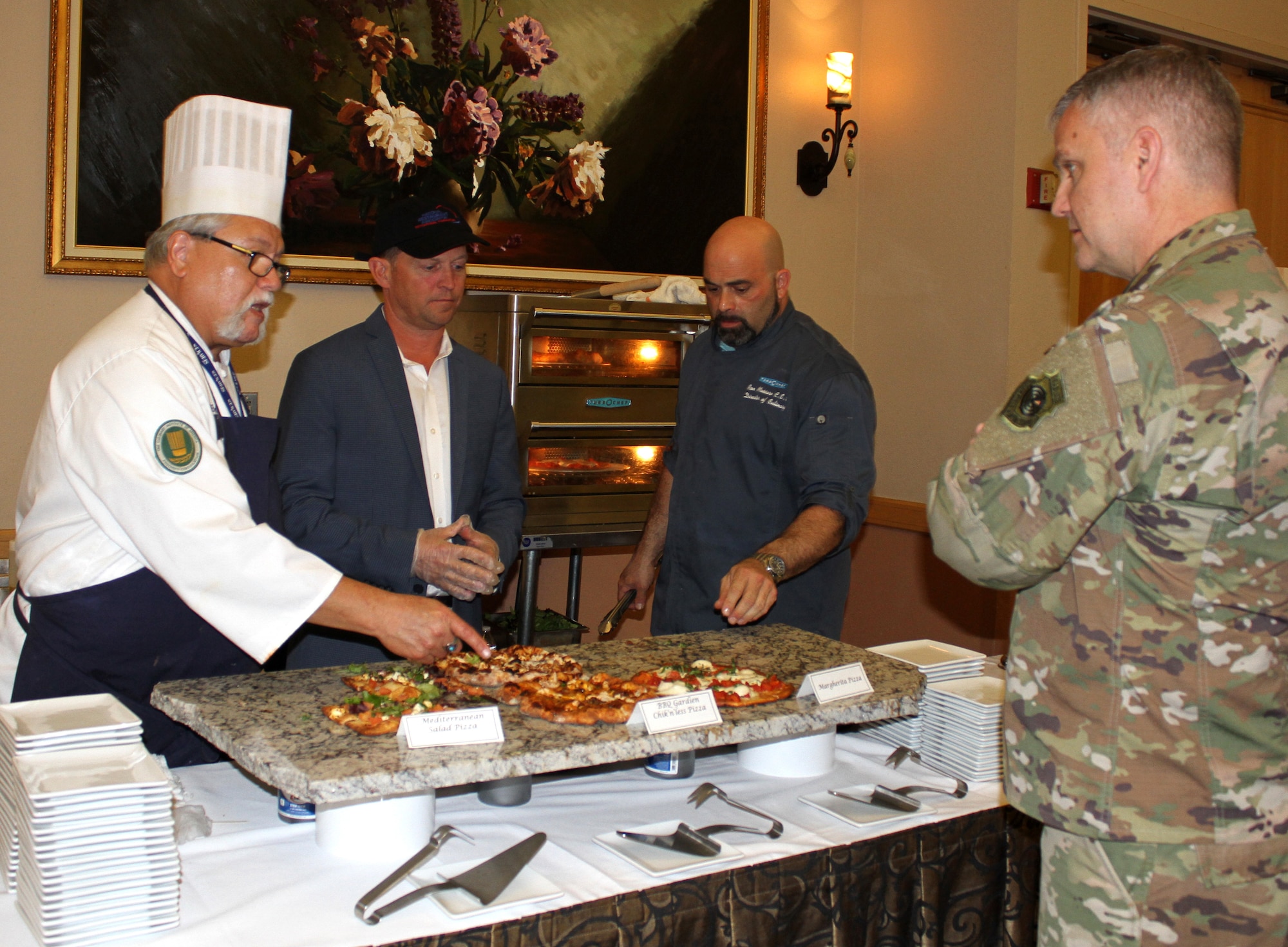 Brig. Gen. Michael Koscheski, an attendee at the General Officer and Senior Executive Service Summit, talks to the culinary team about the healthy cooking methods used to prepare fresh pizzas and grilled salmon during lunch April 10, 2019, at Joint Base San Antonio-Lackland. AFSVA prepared various healthy and nutritious food items to familiarize summit attendees with Healthy Food Initiative, a dining concept being rolled out across the Air Force that’s designed to deliver fresh, healthy, nutritious and tasty food to Airmen. (U.S. Air Force photo by Debbie Aragon)