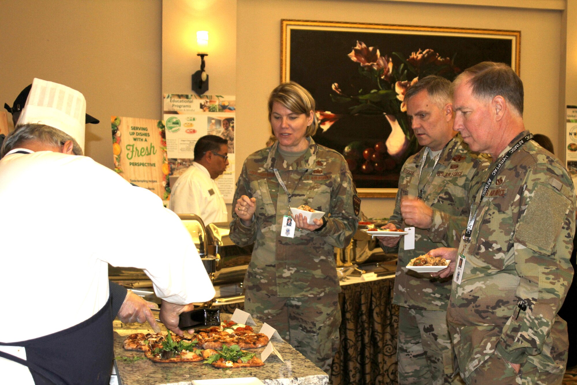 Attendees at the General Officer and Senior Executive Service Summit wait to be served fresh barbecue chik-n-less chicken pizza during lunch April 10, 2019, at Joint Base San Antonio-Lackland. AFSVA prepared various healthy and nutritious food items to familiarize summit attendees with Healthy Food Initiative, a dining concept being rolled out across the Air Force that’s designed to deliver fresh, healthy, nutritious and tasty food to Airmen. (U.S. Air Force photo by Debbie Aragon)