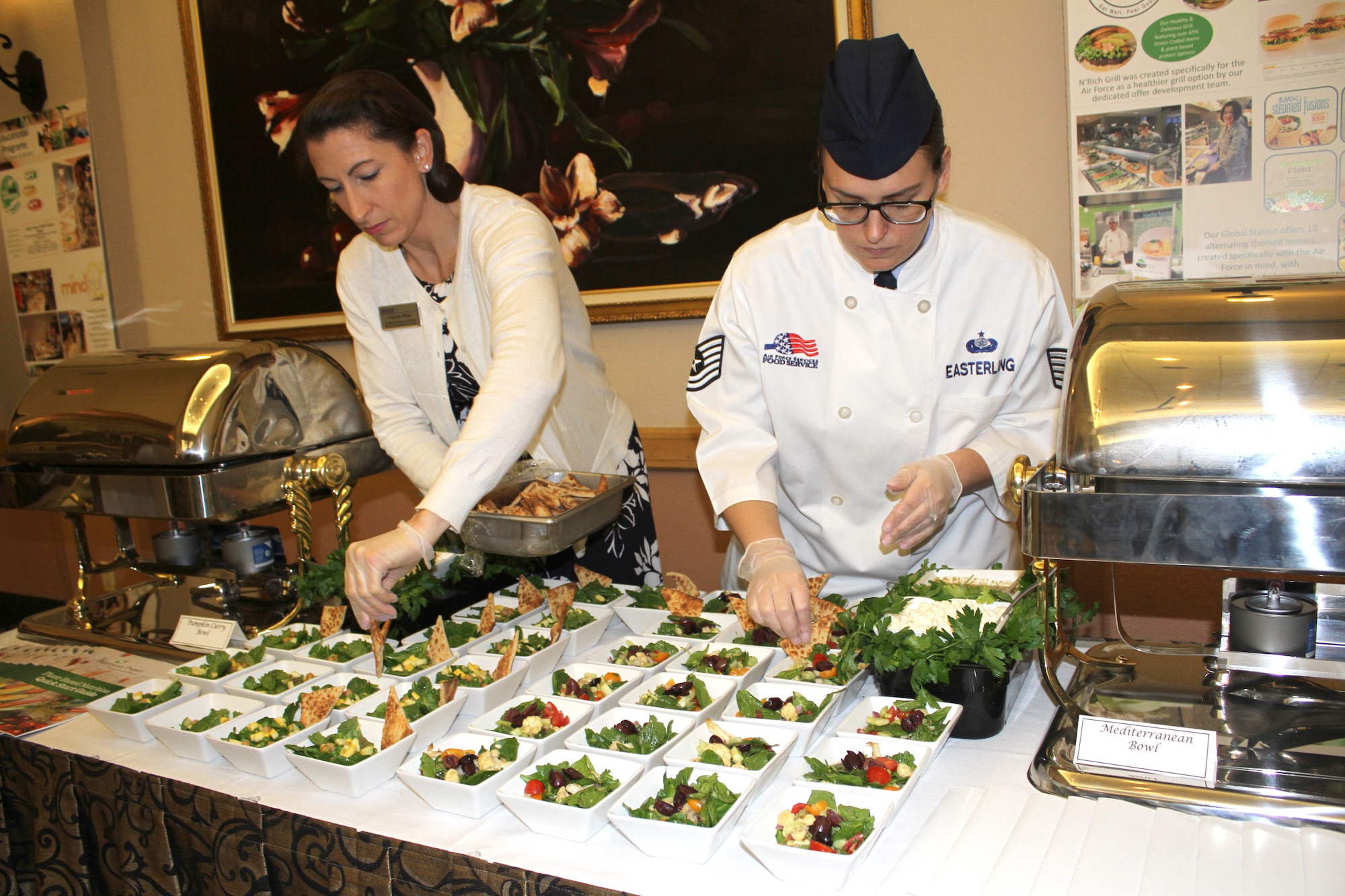Christie Maas and Tech. Sgt. Audrey Easterling, food and beverage managers at the Air Force Services Activity, put the finishing touches on pumpkin curry and Mediterranean bowls for a Healthy Food Initiative lunch during the General Officer and Senior Executive Service Summit April 10, 2019, at Joint Base San Antonio-Lackland. AFSVA prepared various healthy and nutritious food items to familiarize summit attendees with HFI, a dining concept being rolled out across the Air Force. (U.S. Air Force photo by Debbie Aragon)