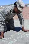 Tech. Sgt. Janai, 799th Air Base Squadron personnelist, participates in a “Chalk The Walk” event to raise awareness of sexual assault and child abuse at Creech Air Force Base, Nevada, April 23, 2019. More than 150 Airmen attended the event, which included a barbecue and information booths manned by members of the Nellis AFB Sexual Assault Prevention and Response office and Mental Health. (U.S. Air Force photo by Master Sgt. Dillon White)