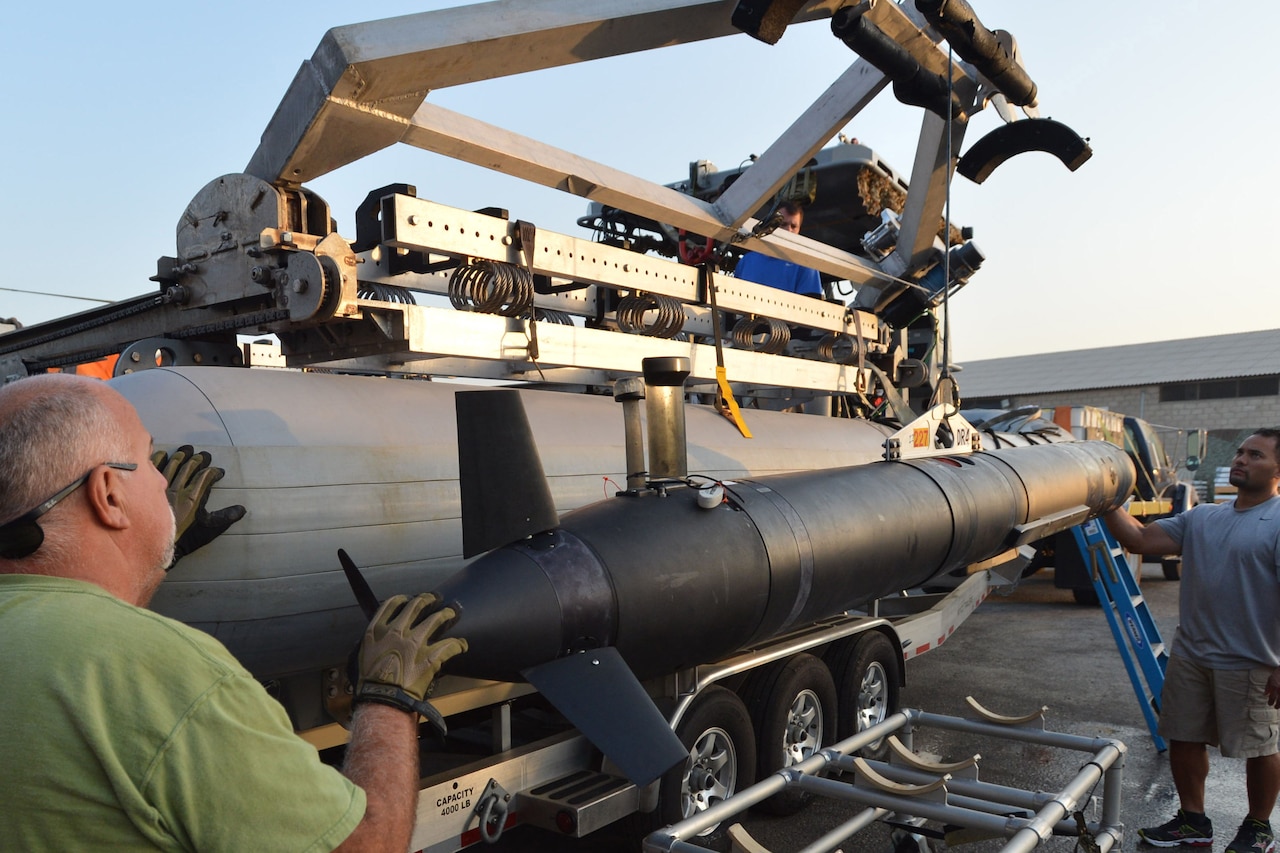 Civilians hoist a device onto a boat.