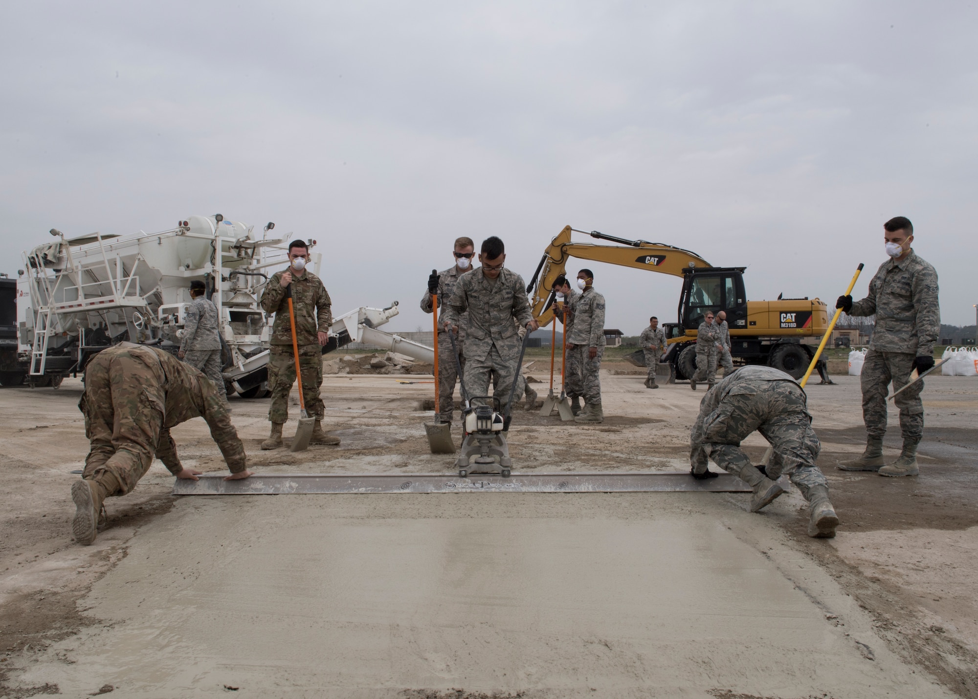 An Airman pulls a vibrating screed during rapid airfield damage repair training