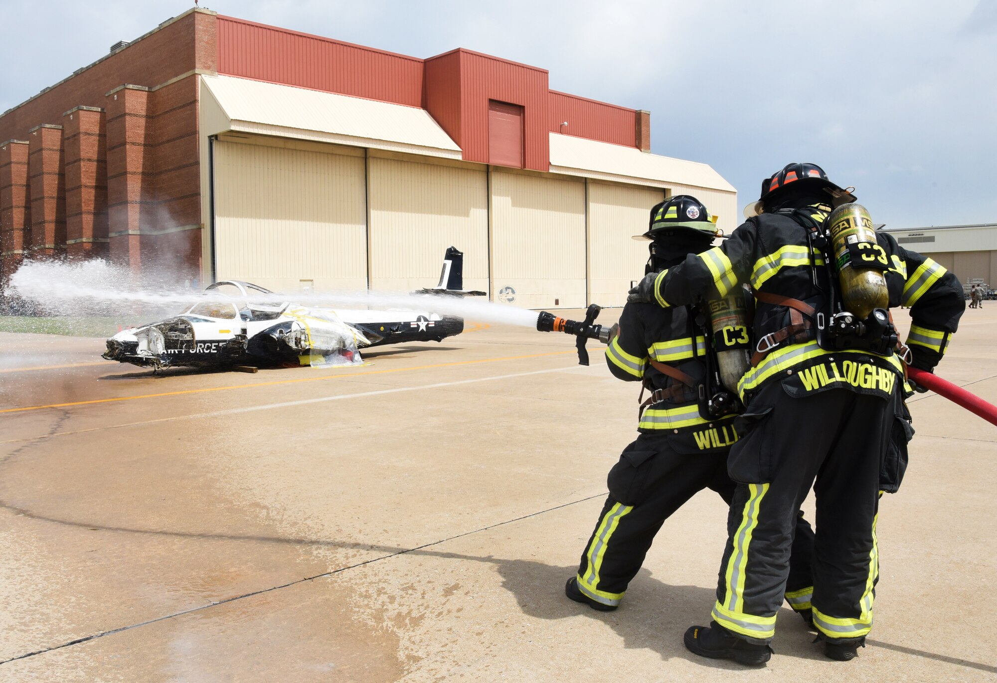 Lt. David Willsey and Capt. Travis Willoughby, with the Tinker Fire Department, respond to an airshow exercise crash scenario April 17, working together to quickly reduce a fire hazard. The fire department was able to respond to the hazards of an aircraft when it crashes, as well as other aspects of the emergency exercise.